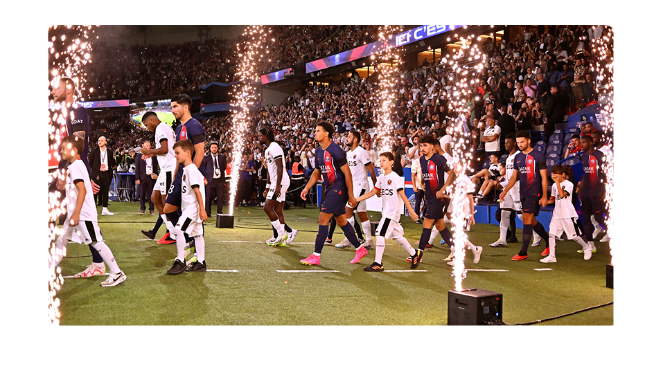 Joueurs de football entrant sur le terrain d'un grand stade sous les feux d'artifice
